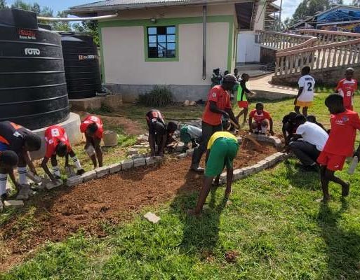 Students at Kijana Global Innovation School creating a brick-lined kitchen garden plot