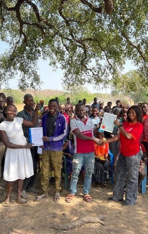 SSA-20260304L-Nuru International-Nuru Ghana team members, Rukaya and Simon, hand out a formal cooperative registration certificate and standard bylaws to a newly formed cooperative.